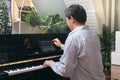 Adult man learning to play piano using digital tablet at home, Happy Asian businessman relaxing by playing piano, Reduce stress