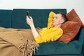 Adult man lie on sofa and chatting on smartphone, side view. Person reclining on pillow under blanket and lounging.
