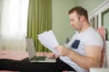 Adult man lying in his bed while he is working from home on his laptop looking on the screen Royalty Free Stock Photo