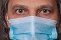 Adult man in a medical mask. Close-up eyes. Syringe in hand