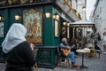 Adult man playing acoustic guitar on the outdoors cafe with people walking on a lively city street