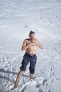 Adult man practicing cryotherapy, in the snow