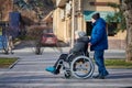 Adult man rolls his disabled mother on wheelchair, careful relationships with disabled person