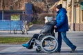 Adult man rolls his disabled mother on wheelchair, careful relationships with disabled person