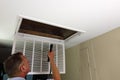 Adult Man Shining Flashlight Into HVAC Intake Vent in a Home Entry