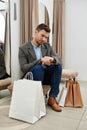 Adult man sitting in fitting room, looking at watch Royalty Free Stock Photo