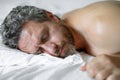 Adult man sleeps in white bed. Handsome shirtless man sleeping in bed at bedroom. Hispanic mature man sleeping at home Royalty Free Stock Photo