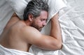 Adult man sleeps in white bed. Handsome shirtless man sleeping in bed at bedroom. Hispanic mature man sleeping at home Royalty Free Stock Photo