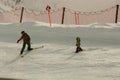 An adult man, standing on skis, teaches a small child to ski Royalty Free Stock Photo