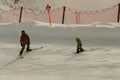 An adult man, standing on skis, teaches a small child to ski Royalty Free Stock Photo