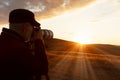 An adult man takes pictures of a picturesque sunset in the mountains with a long lens fixed on a tripod. Copy space