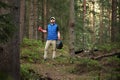 Adult man volunteer in red gloves removes plastic trash in forest, caring for environment