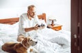 Adult man waked up and plays PC games sitting in bed, his dog wa