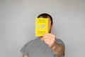 Adult man wearing t-shirt holding yellow International Certificate of Vaccination on gray background