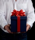 Adult man in a white shirt holds a blue gift cardboard box with a red bow Royalty Free Stock Photo