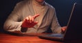 An adult man works on a laptop and periodically makes hand gestures and touches the transparent screen with his finger