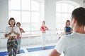 Adult man yoga instructor trains and teaching group of women yoga exercises for maintaining health care in white class