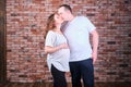 An adult married couple a man and a woman in casual clothes kiss against the background of a red brick wall Royalty Free Stock Photo