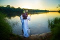 Adult mature brunette woman in a white dress, sundress and a wreath of flowers in summer in water of river or lake in Royalty Free Stock Photo