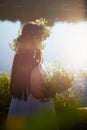 Adult mature brunette woman in a white dress, sundress and a wreath of flowers in summer by the water of river or lake Royalty Free Stock Photo