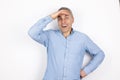 Adult mature handsome man with grey hair wearing blue shirt looks surprised standing on isolated white background