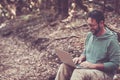 Adult mature man use laptop computer with roaming internet connection in the middle of the woods - concept of remote worker and Royalty Free Stock Photo