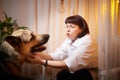 Adult mature woman with big shepherd dog in white shirt. Room with girl and calm cozy evening atmosphere with Royalty Free Stock Photo