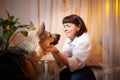 Adult mature woman with big shepherd dog in white shirt. Room with girl and calm cozy evening atmosphere with Royalty Free Stock Photo