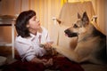 Adult mature woman with big shepherd dog in white shirt. Room with girl and calm cozy evening atmosphere with Royalty Free Stock Photo