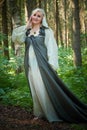 Adult mature woman 40-60 in a green long fairy dress in forest. Photo shoot in style of dryad and queen of nature. Fairy