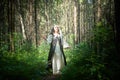 Adult mature woman 40-60 in a green long fairy dress in forest. Photo shoot in style of dryad and queen of nature. Fairy