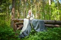 Adult mature woman 40-60 in a green long fairy dress in forest. Photo shoot in style of dryad and queen of nature. Fairy