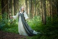 Adult mature woman 40-60 in a green long fairy dress in forest. Photo shoot in style of dryad and queen of nature. Fairy