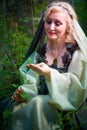 Adult mature woman 40-60 in a green long fairy dress in forest. Photo shoot in style of dryad and queen of nature. Fairy