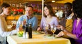 Adult men and women having friendly meeting at dinner in restaurant