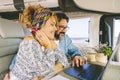 Adult man and woman using together a laptop inside a modern camper van. Couple in digital nomad online job van life lifestyle. Royalty Free Stock Photo