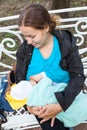 Adult mother looking at her newborn child while holding arms and breastfeeding in park Royalty Free Stock Photo