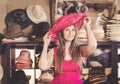 Adult nice woman try on pink boater hat in shopping mall