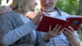 Adult parents admiring photos in family album remembering youth, happy moments