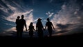 Adult parents and three teenage children are walking in the field at sunset, silhouette Royalty Free Stock Photo