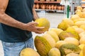 Adult person selecting fresh melon in supermarket. Man holding a big yellow melon in his hands Royalty Free Stock Photo