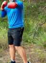 Adult plump athlete in blue uniform and red leather boxing gloves stand in the middle of a green meadow Royalty Free Stock Photo