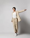 Adult pretty brunette woman walks in beige business smart casual pantsuit and sneakers. Stylish business female wear