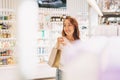 Adult pretty smiling woman with dark hair in the cosmetics and perfume store, holiday shopping