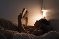 Adult reading a book in bed with child at night Royalty Free Stock Photo