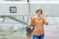 An adult red-haired woman with a serious face stands with crossed fingers in front of a boarding bridge on a plane at the airport Royalty Free Stock Photo