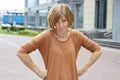 An adult redhead woman in casual clothes with a serious expression stands with a cookie on her hips. Royalty Free Stock Photo