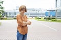 An adult redhead woman in casual clothes stands in the street with her arms crossed in annoyance Royalty Free Stock Photo