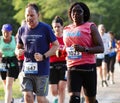 Adult runners racing a 5K in a park on a summer evening