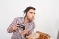 Adult silly bearded man with short dark hair in headphones, playing online games on personal computer with controller